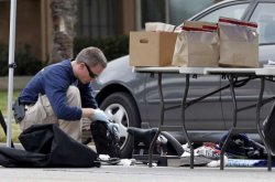 An FBI agent goes through a laptop bag in front of the Redlands residence and vehicle belonging to the alleged shooters in connection to the Wednesday massacre in San Bernardino, California, Dec. 3, 2015.