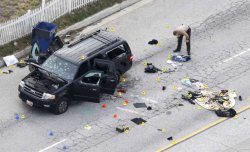 A law enforcement officer looks over the evidence near the remains of a SUV involved in the attack is shown in San Bernardino, California Dec. 3, 2015. Authorities on Thursday were working to determine why a man and a woman opened fire at a holiday party of his co-workers in Southern California, killing 14 people and wounding 17 in an attack that appeared to have been planned.