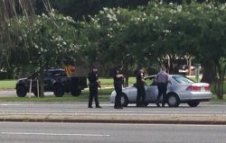 Authorities talk to the driver of a car near an area where several officers were shot while on duty less than a mile from police headquarters, Sunday, July 17, 2016, in Baton Rouge, La.