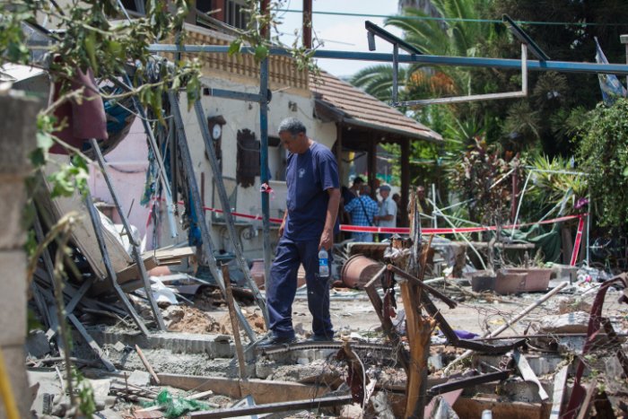 A man inspects the damage to a house following a rocket attack by terrorists from the Gaza Strip on the Israeli town of Yehud, beside Israel's Ben Gurion International Airport, on July 22, 2014. (Photo credit: Yonatan Sindel/Flash90)