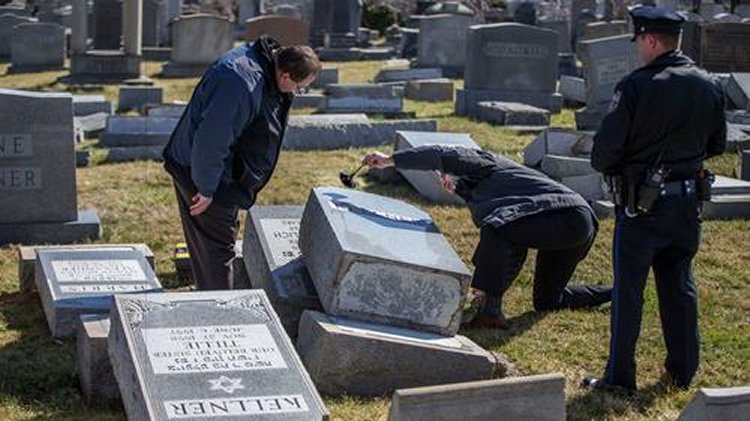 Police on Sunday dust for fingerprints on a headstone that was knocked down at Mt. Carmel Cemetery in Philadelphia. (Michael Bryant / Associated Press)