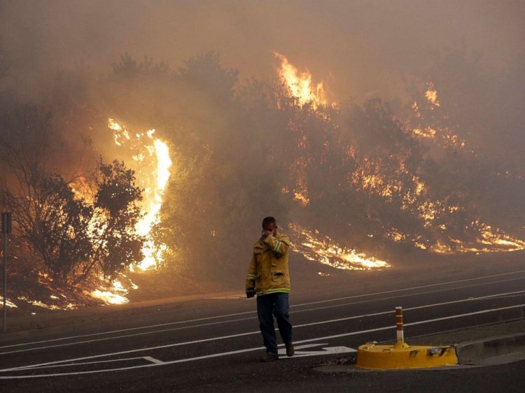 A firefighter covers his eyes as he walks past a burning hillside in Santa Rosa, Calif., Oct. 9, 2017.