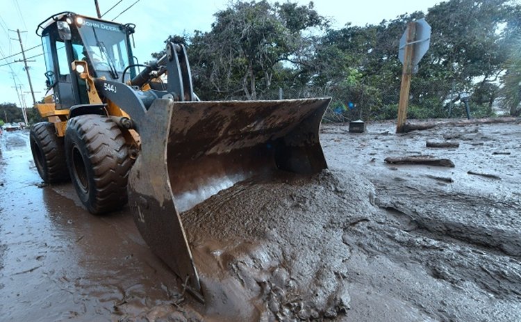 A bulldozer clears mud off the road near a flooded section of a freeway in Montecito, Calif., on Tuesday. Mudslides unleashed by a ferocious storm demolished homes in Southern California and killed more than a dozen people, police said. (Frederic J. Brown/AFP/Getty Images)