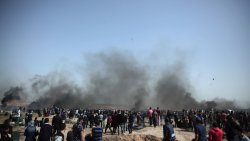 Palestinian protestors creating black smoke from burning tires at the border fence between Gaza and Israel
