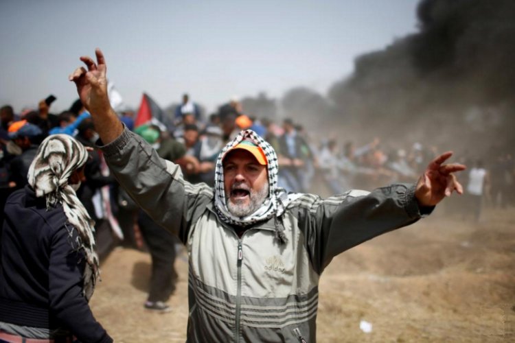 A man shouts as Palestinian demonstrators remove part of the Israeli barbed wire during clashes with Israeli troops at a protest demanding the right to return to their homeland, at the Israel-Gaza border, east of Gaza City, April 13, 2018. REUTERS/Mohammed Salem