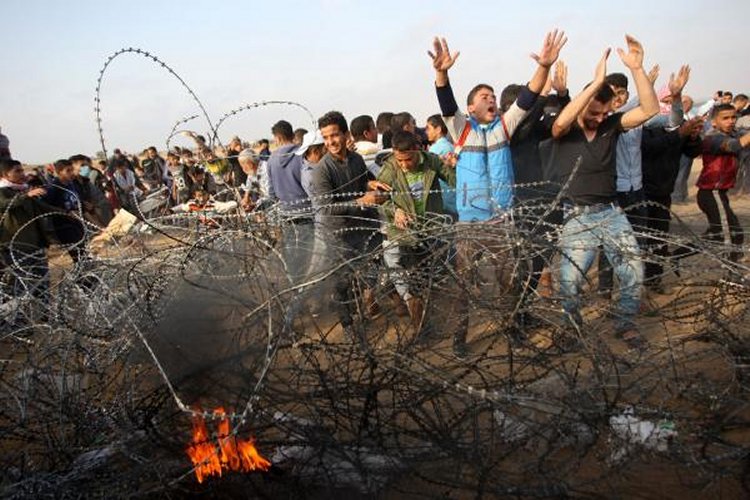 Palestinian demonstrators try to pull down part of a fence as they stage a protest within 