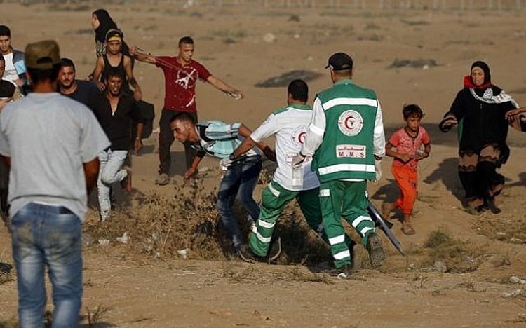 Palestinian paramedics help a protester at the Israel-Gaza border, east of Gaza city, on October 12, 2018. (Said Khatib/AFP)