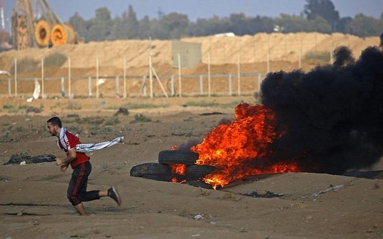 A Palestinian protester runs by burning tires at the Israel-Gaza border, east of Gaza city, on October 12, 2018. (Said KHATIB / AFP)