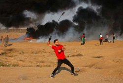 A Palestinian protester uses a slingshot to throw a rock at Israeli forces along the Israel-Gaza border east of Gaza city on October 12, 2018