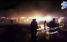 This frame grab from video provided on Wednesday, May, 9, 2018 by Syria News, shows people standing in front of flames rising after an attack on an area known to have numerous Syrian army military bases, in Kisweh, south of Damascus, Syria on Tuesday. (Syria News, via AP)