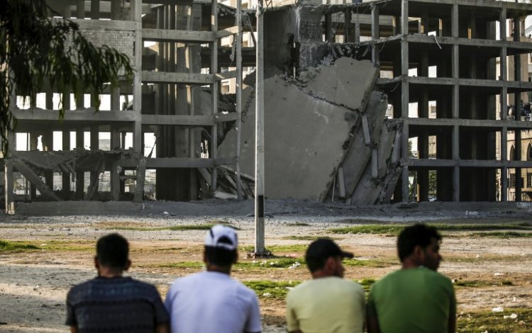 Palestinian youths look at a building that was damaged by an Israeli air strike in Gaza City on July 14, 2018 (AFP /Mahmud Hams)
